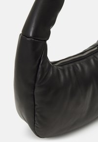 Čierna kožená kabelka s zaobleným, polstrovaným tvarom. Obsahuje zips a má jemnú textúru s decentnými švami.