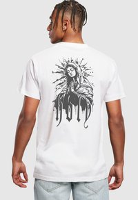 White cotton t-shirt featuring a black graphic of a praying figure with a halo and splatter design on the back.