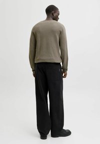 Olivgrön tr�öja med långa ärmar och avslappnad passform, kombinerad med svarta vida byxor med en bakficka. Mjuk textur, minimalistisk design.