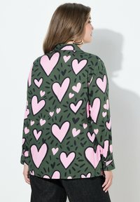 Groene shirt met een overal patroon van roze harten, met zwarte accenten en lange mouwen, een slim fit, en knoopmanchetten.