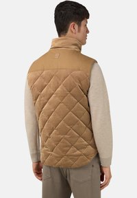 Šviesiai rudas siūtuotas liemenė su šonkauliniovelveto tekstūra nugaroje. Pilki rankovės, aukštas apykaklė ir maža prekės ženklo etiketė ant kaklo.