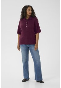 Polo en maille bordeaux à manches courtes avec col et patte à cinq boutons, associé à un jean large bleu clair et des ballerines noires.