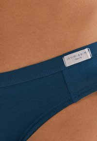 Marinblå bikini i bomull med mjukt elastiskt midjeband märkt "intimissimi Natural," med släta sömdetaljer och en figurnära design.