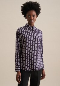 Camicia button-up di colore viola scuro con un motivo a catena bianca. Presenta un colletto a punta, maniche lunghe e chiusure a bottoni. Tessuto con una texture liscia.