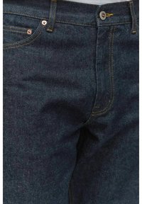 Mörkblå denimjeans med gula sömmar, med en klassisk femfickdesign och en midja med silverknapp.