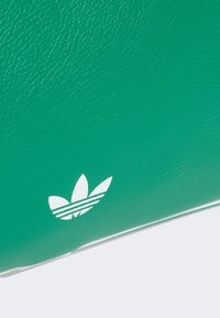 Zelena kožna torba s teksturiranom površinom i bijelim Adidas logotipom s trima prugama. Dizajn je elegantan i minimalistički.