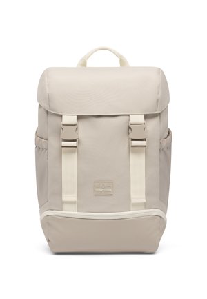 Beige rectangular backpack with top flap, dual buckle straps, side pockets, a front logo patch, and a handle on top.