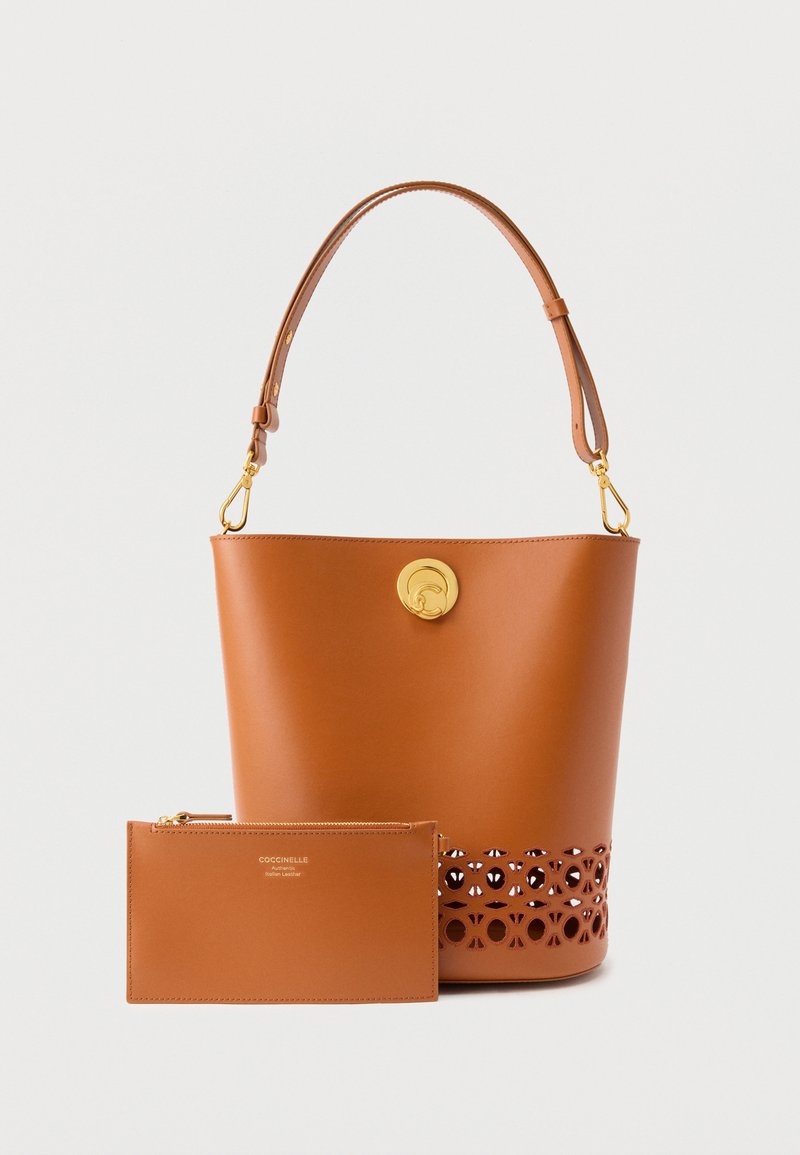 Δερμάτινη τσάντα τύπου κάδος σε ταμπά χρώμα με χρυσό κούμπωμα, ρυθμιζόμενη λουρίδα και τσαντάκι με φερμουάρ που ταιριάζει, με λογότυπο της μάρκας μπροστά.