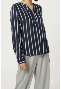 Blouse à manches longues rayée bleu marine avec un col en V, rayures verticales blanches et patte de boutonnage ; tissu lisse et coupe décontractée.