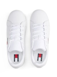 Weiße Sneaker aus synthetischem Material. Die Merkmale umfassen flache Schnürsenkel, eine runde Zehenpartie und ein Logo-Tag mit roten, weißen und blauen Akzenten.