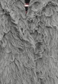 Gilet grigio e texturizzato realizzato in materiale morbido, caratterizzato da un design denso e ondulato con un aspetto soffice e peloso. Nessun tipo di chiusura o motivo visibile.