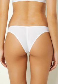 Perizoma bianco senza soluzione di continuità, realizzato in materiale sottile e liscio. Include un elastico stretto in vita e una copertura minima con una finitura pulita.