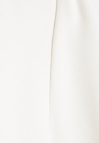 Tissu blanc avec une surface lisse et légèrement texturée. Le design présente des lignes épurées et un éclat subtil, mettant en avant la simplicité.