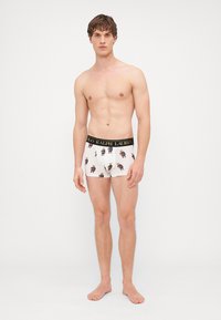 Biele boxerky so vzorom z opakujúcich sa kreslených postavičiek, zakončené čiernym pásom s nápisom "POLO RALPH LAUREN."