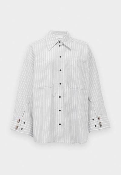 Light gray striped oversized button-up shirt, featuring two front pockets and contrasting black buttons. Soft fabric with layered cuffs.