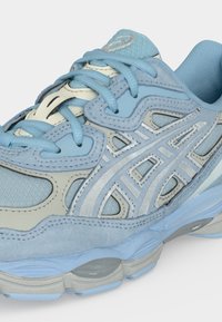 Lys blå og grå løpesko med mesh, semsket skinn, syntetiske overlegg, mønstret logo, polstret krage og snøring.