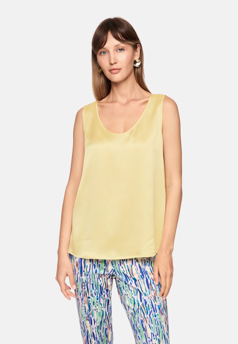 Yellow satin sleeveless top with a scoop neckline, paired with patterned pants featuring blue, green, and pink abstract designs.