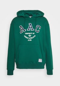 Grön huvtröja gjord av mjukt tyg med vit text "AAC" och "PROPERTY OF ADIDAS ATHLETIC CLUB". Inkluderar en framficka och logotag.
