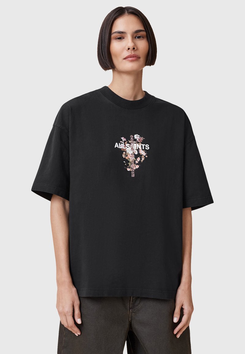 T-shirt nera in cotone con collo rotondo e maniche corte. Presenta una stampa grafica floreale e testo del marchio in bianco. Vestibilità comoda e texture liscia.