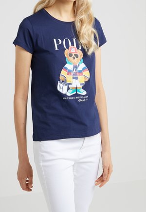 T-shirt en coton bleu marine à col rond avec un motif d'ours en tenue multicolore. Associé à un pantalon blanc, manches courtes, coupe décontractée.