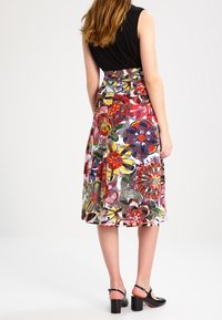 Jupe midi florale avec un motif coloré featuring des fleurs rouges, jaunes et bleues. Fabriquée en tissu léger, avec une taille ajustée et une forme évasée.