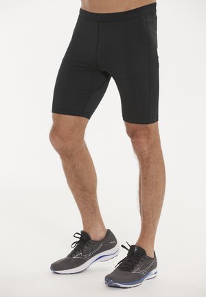Shorts de sport noirs en tissu extensible, avec une texture lisse et une coupe ajustée. Pas de motifs visibles ni de détails en métal.