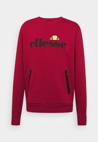 Sweatshirt rouge avec un col rond, logo noir sur le devant et deux poches latérales zippées. Fabriqué en tissu doux et texturé.