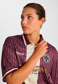 Koszulka polo w bordowo-kremowe paski z kołnierzykiem, z logo i marką na piersi oraz kontrastowymi mankietami i obszyciem kołnierza.