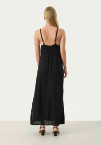 Schwarzes Maxikleid mit dünnen, verstellbaren Trägern, gerafftem Rücken und fließendem Stoff. Glatte Textur und knöchellange Schnittform. Schlichtes Design.