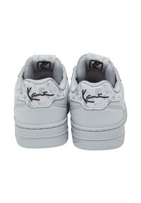 Gray sneakers with a smooth material, rounded shape, padded tongue, and textured accents. Features a logo and subtle pattern on the heel.