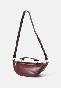 Sac en cuir bourgogne à bandoulière avec fermeture éclair, de forme plate, poignée courte et bandoulière réglable ; doté d'accents en matériel doré.