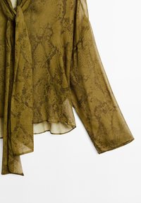 Olivenfarvet bluse i let, let gennemsigtigt materiale. Har et slangeskindsmønster, lange ærmer og en bundet halsudskæring.