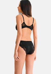 Soutien-gorge noir avec dentelle et culotte de bikini taille haute. Détails en dentelle florale transparente sur les côtés, tissu lisse, bretelles réglables et fermeture à crochet au dos.