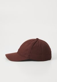 Căciulă de baseball bordeaux cu o margine curbată, fabricată din material de bumbac. Prezintă accente brodate și orificii de ventilație pe coroana căciulii.