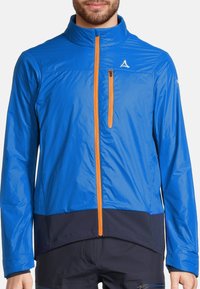 Veste légère bleue avec fermeture éclair orange, col haut et panneau inférieur bleu marine. Tissu texturé et détail de logo réfléchissant sur la poitrine.
