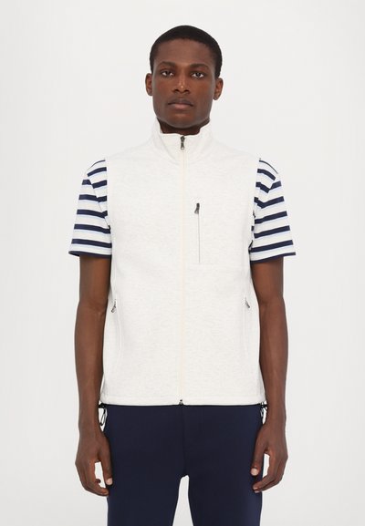 Veste sans manches gris clair avec fermeture éclair à l'avant, deux poches latérales, et un t-shirt à manches courtes rayé bleu et blanc en dessous.