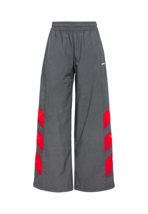 Šedé kalhoty širokého střihu s elastickým pasem, které mají odvážné červené chevronové akcenty po stranách. Vyrobeny z lehkého, hladkého materiálu.