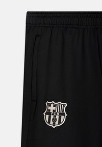 Black athletic pants with an elastic waistband, featuring side pockets and an embroidered FCB club logo in gray on the thigh.