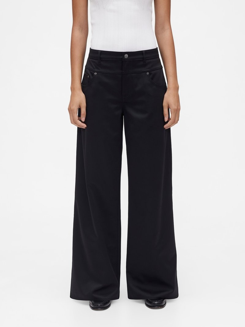 Pantalon noir à jambes larges fabriqué dans un tissu lisse et mat. Comprend des poches avant et une fermeture à bouton avec des accents métalliques.