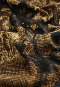 Textil mit einem komplexen Muster in tiefbraun und Gold. Der Stoff hat eine gerippte Textur mit einem glänzenden Finish und präsentiert elegante Blumenmotive.