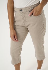 Beige cropped pants made of striped fabric, featuring a high waist, front pockets, and a button closure.