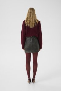 Burgundy knit sweater, black leather mini skirt, burgundy tights, and high-heeled shoes, viewed from behind against a plain background.
