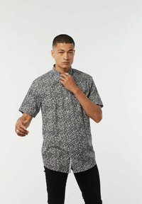 Korte mouwen shirt met een zwart-wit bloemenpatroon, kraagontwerp, knopen aan de voorkant en een ontspannen pasvorm.