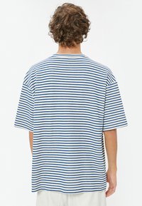 Stribet T-shirt lavet af blødt stof i hvid og blå. Har korte ærmer og en afslappet pasform, med vandrette striber, der dækker hele tøjet.