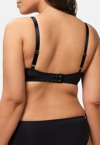 Zwarte beha met verstelbare bandjes, een zachte textuur en een haak-en-oogsluiting aan de achterkant met gouden accenten.