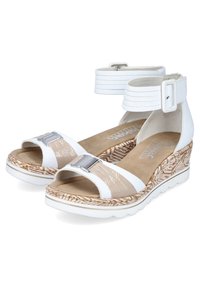 Sandales compensées blanches avec une sangle beige texturée, accent de boucle en argent et un design tissé sur la semelle. Fini en matériau lisse et brillant.