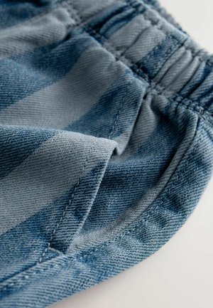Blåstribet denimstof har en elastisk talje, med en glat overflade og synlige syninger langs kanterne.