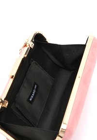 Sac à main en velours rose avec un cadre en métal doré, doté d'un intérieur en tissu noir et d'une poche pour étiquette. L'intérieur a une texture lisse.