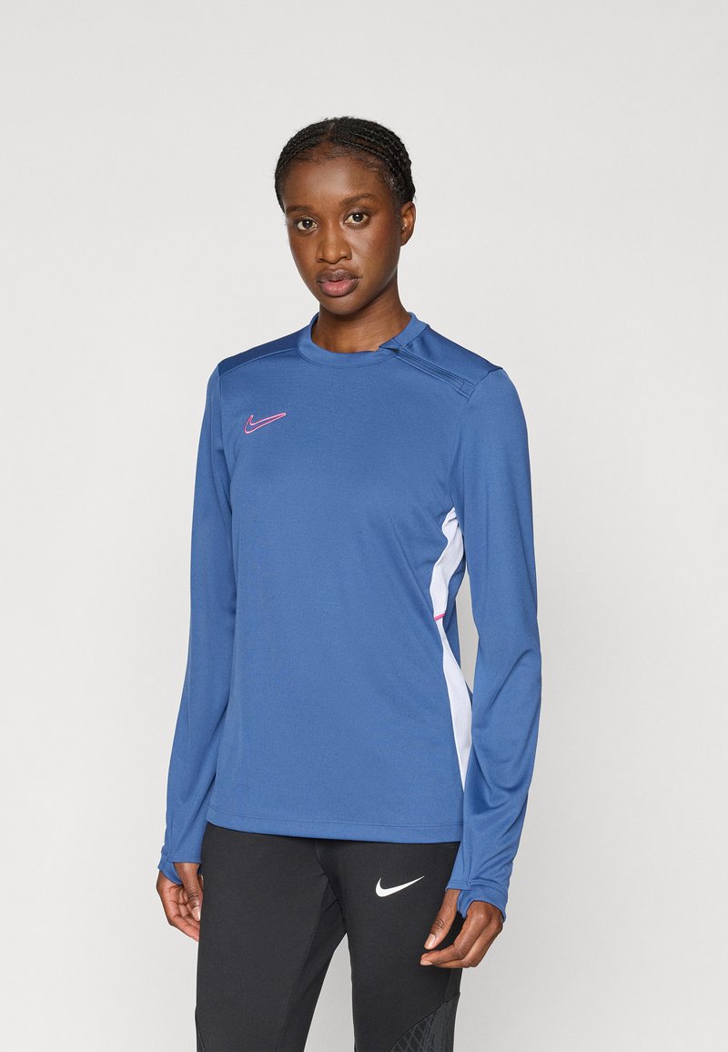 Αθλητικό μπλουζάκι με μακριά μανίκια σε σκούρο μπλε, με ροζ λογότυπο της Nike, λευκές πλαϊνές ρίγες και υφασμάτινη υφή. Κοντή εφαρμογή με σχέδιο λαιμόκοψη.