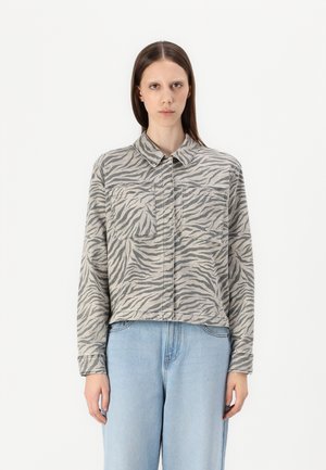 Kort skjorte i grå med sorte zebra-striper, med krage, knappelukking og to frontlommer. Laget av denimstoff.